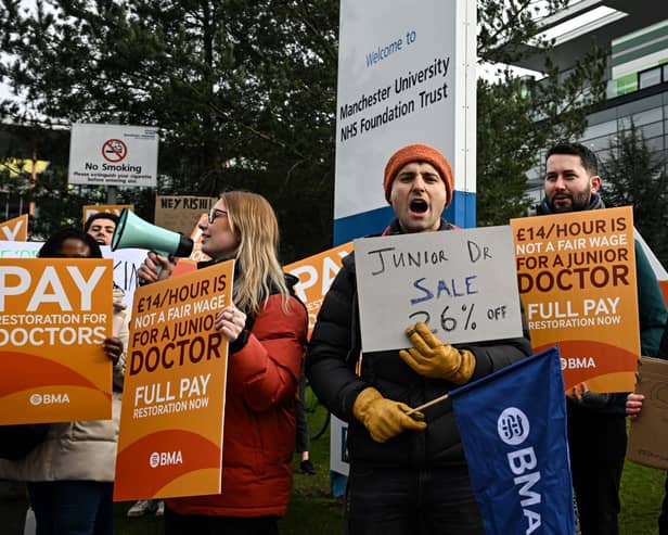 Demonstrators hold placards as they take part in a protest by junior doctors, amid a dispute with the government over pay, outside of Saint Mary's Hospital, in Manchester, on March 15, 2023. 