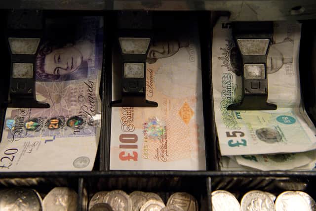 An open cash register containing pound coins and notes is pictured in a convenience store in London