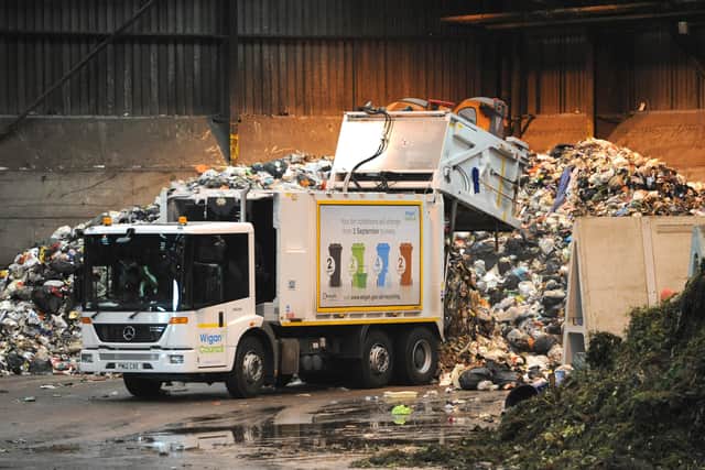Bin collections:  One of the bin wagon tips it's load next to a pile of green waste at Kirkless Household Waste Recycling Centre, Makerfield Way, Higher Ince