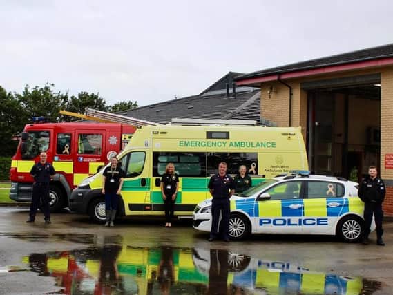 Rachel O'Neil, second from left, with members of the emergency services and their vehicles, which have been adorned with gold ribbons to mark Teenage Cancer Awareness Month.