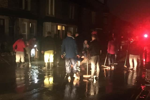 Residents attempting to stop floodwater entering properties in High Road.