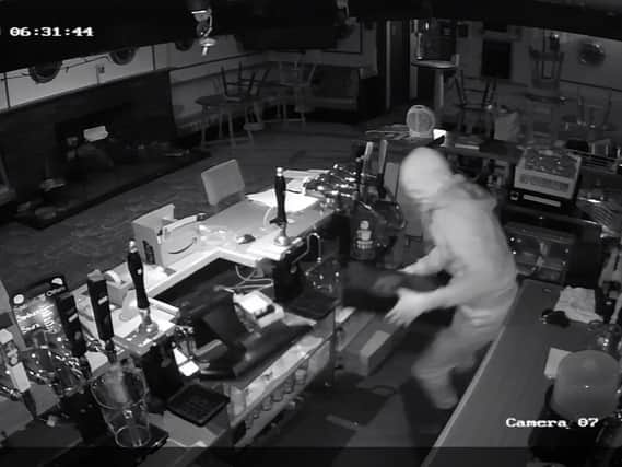A CCTV image of the thief stealing the till drawer.