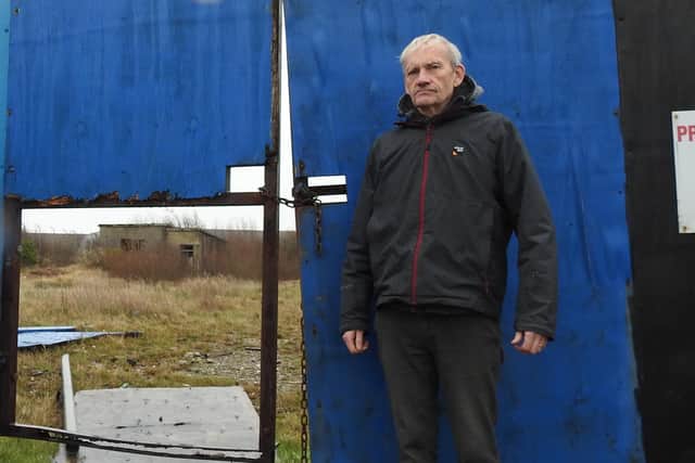 Morecambe Town Councillor Jim Pilling next to the blue fencing.