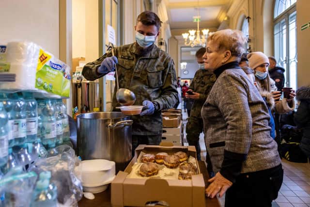 A soldier serves soup to a Ukrainian woman in the building of the main railway station of Przemysl which has been turned into a temporary reception centre for refugees from Ukraine fleeing the conflict in their country, in eastern Poland on February 25, 2022, one day after Russia launched a military attack on its neighbour Ukraine. Photo by WOJTEK RADWANSKI/AFP via Getty Images