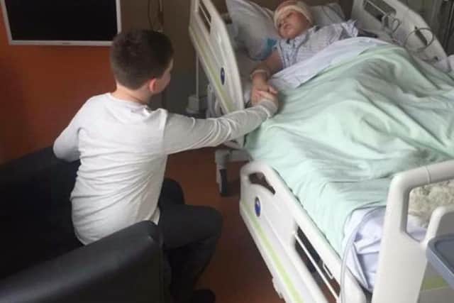 Callum holds Reece's hand in hospital during Reece's treatment for brain cancer.