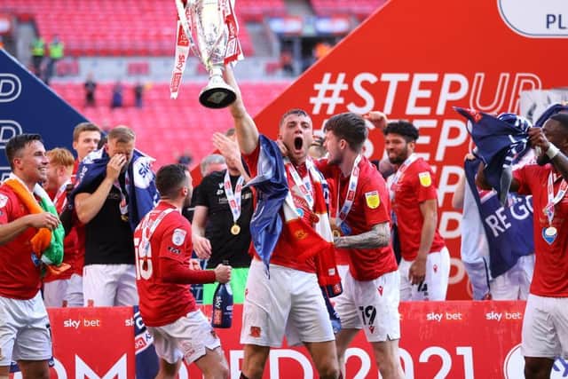 Morecambe skipper Sam Lavelle lifts the League Two play-off final winners' trophy