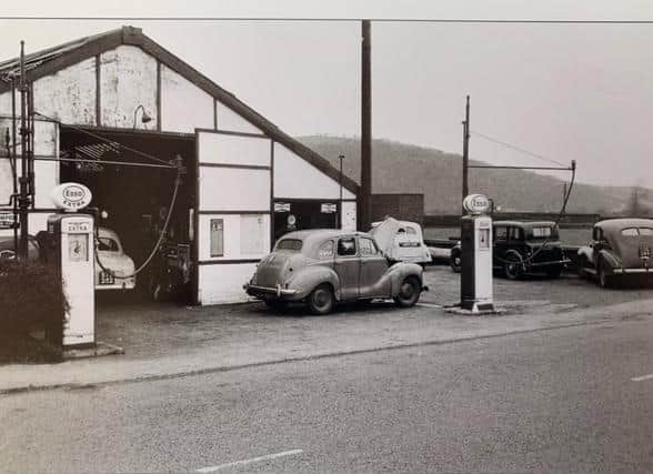 A busy T.N.T garage around the middle fifties, showing a Standard Eight just inside the garage. The car with the raised bonnet we think is an A40. The white car could be a 1940s Austin, on the right of the photograph is a 1930s Austin, and on the extreme right is possibly a Standard Flying 12. Note how close to the road the long arm petrol pumps were in the 1950s.