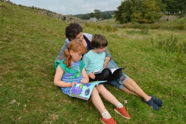 Jane Huddleston reading with her two children.