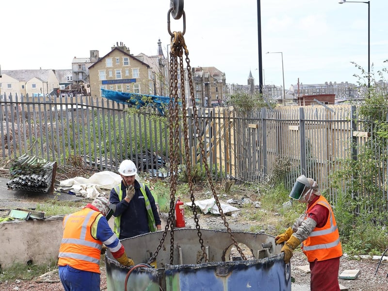 Workmen prepare for the final part of the tower to be lifted away.