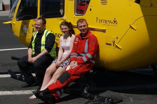Alice Roberts one year after her accident at the NWAA base in Blackpool, sitting with the pilot (left) and one of the paramedics (right) who helped rescue her.
