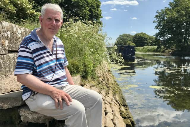 Nicholas Thorn, a parish councillor, at the Lancaster Canal near Glasson Marina and Glasson Dock. The canal water level is low with banks exposed and a canal boat is tilted on its side.