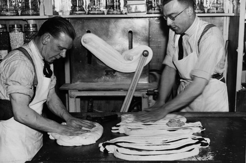 Two rock makers in Morecambe prepare new sweets for the Easter rush, carefully rolling in the lettering, in April 1939.