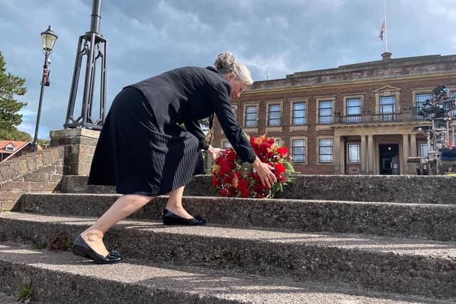 Coun Joyce Pritchard places flowers on the steps to the sunken gardens at Morecambe Town Hall.
