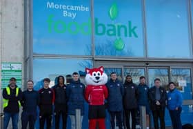 Christie the cat, Morecambe FC players and representatives of Morecambe Bay Foodbank outside the premises on Westgate. People can donate to the foodbank this Saturday ahead of the Morecambe FC match against Charlton Athletic.
