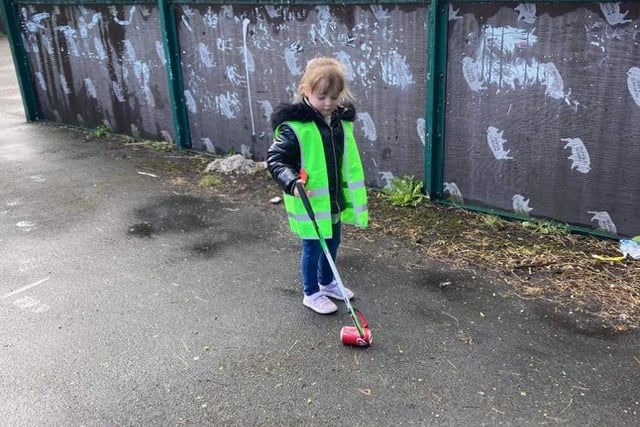 A little girl picks up a solitary drinks can on the litter pick.