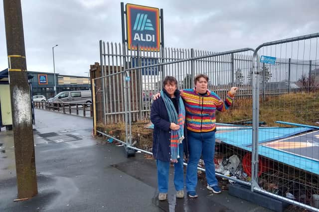 Karen Conroy and her daughter Josie at the temporary fencing erected near Aldi in Morecambe after stormy weather blew the wooden fencing down with artwork on it. The artwork can be seen on the blue hoarding behind the fence.
