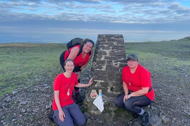 Some of the staff taking part in the challenge, with one of the stones and the Peter Rabbit toy they left at a trig point.