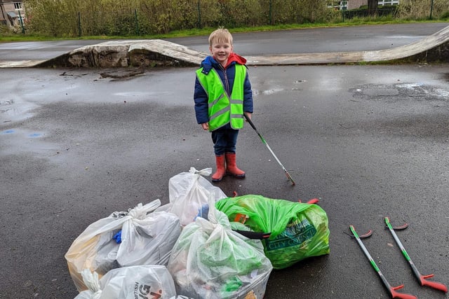 A little boy looks pleased with himself in front of bags of litter he and other children collected.