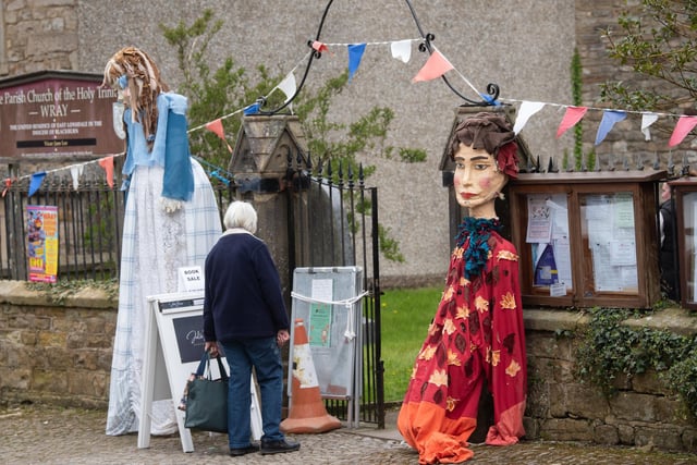 Two scarecrows at the entrance to the church which is holding a book sale at Wray Scarecrow Festival 2024.