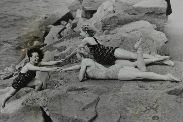 Whitsun holidaymakers give a helping hand to their companion climbing the rocks after a bathe in the sea at Morecambe.