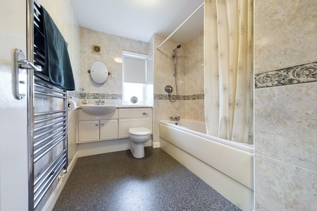 The stylish family bathroom contains a bath with overhead shower, hand basin and wc.