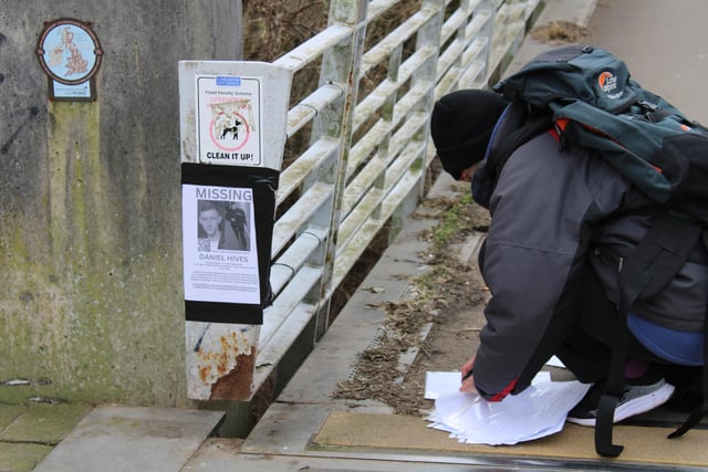 A supporter helps put up posters appealing to the public for help.