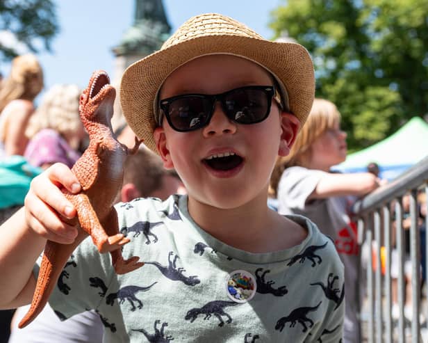 Leo, five, with his toy dinosaur as he awaits Zeus the giant T-Rex in Dalton Square.
