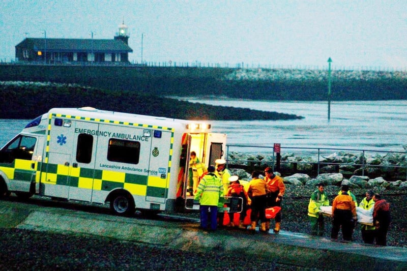 Rescue workers carry bodies into an ambulance at Morecambe Lifeboat Station on Friday February 6, 2004, after the Morecambe Bay cockling disaster in which 23 Chinese people lost their lives.