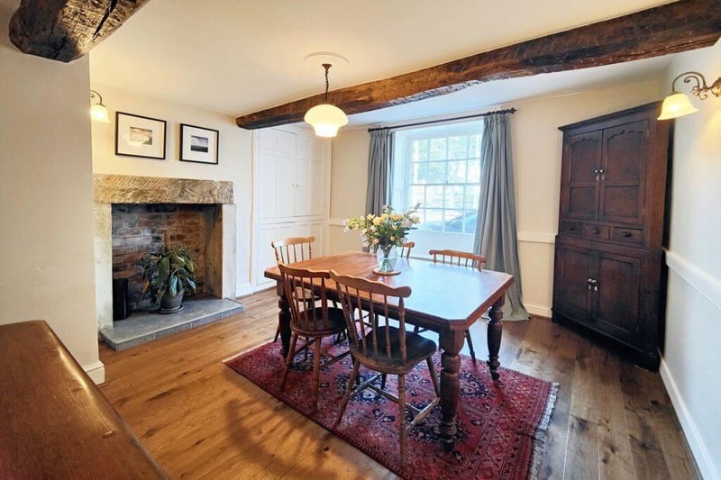The dining room has an exposed stone fireplace and wood flooring.