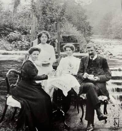 A tea party around 1915 being held on the narrow strip of land between the mill race and the River Roeburn. From left: Cissie Stephenson (a domestic servant), Esther Swindlehurst, William Carradus. William Carradus was head woodsman for the Hornby Castle estate. He found the upper floors of the old mill a good place to rear chickens. Behind the party can be seen the penstock that controlled the flow of water from the river down the mill race. Picture courtesy of David Kenyon.