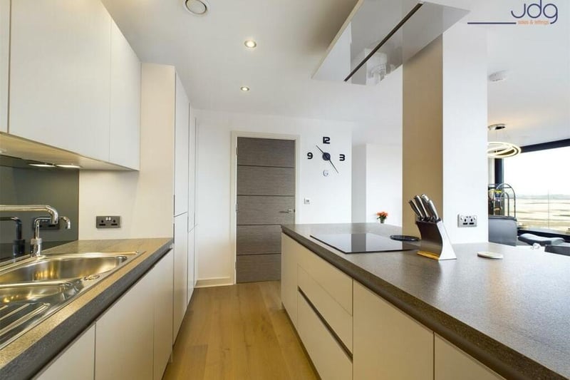 The ultra sleek kitchen is open to the living space, separated by an island/breakfast bar.