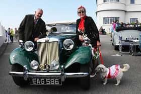 A man, a lady and a dog all in vintage clothing next to a vintage MG car at the vintage festival at the weekend.