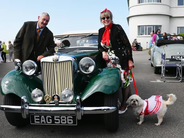 A man, a lady and a dog all in vintage clothing next to a vintage MG car at the vintage festival at the weekend.