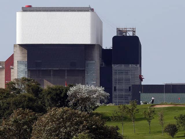 Golfers are pictured on a course against the backdrop of EDF's Heysham 2 Nuclear Power Station in north-west England, on September 24, 2008. AFP PHOTO/PAUL ELLIS (Photo credit should read PAUL ELLIS/AFP via Getty Images)