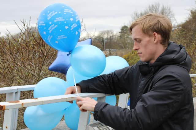 Robbie Hives ties balloons to the Millennium Bridge to mark his brother Daniel's 29th birthday. Photo: Joshua Brandwood