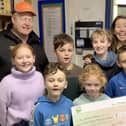 The children present a cheque for £911.68 to Mike Davies from the charity,