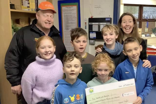 The children present a cheque for £911.68 to Mike Davies from the charity,