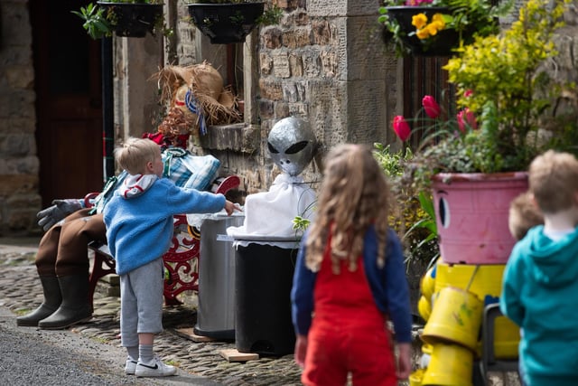 Children enjoy looking at and interacting with the scarecrows at the Wray Scarecrow Festival 2024 with a sci-fi theme.