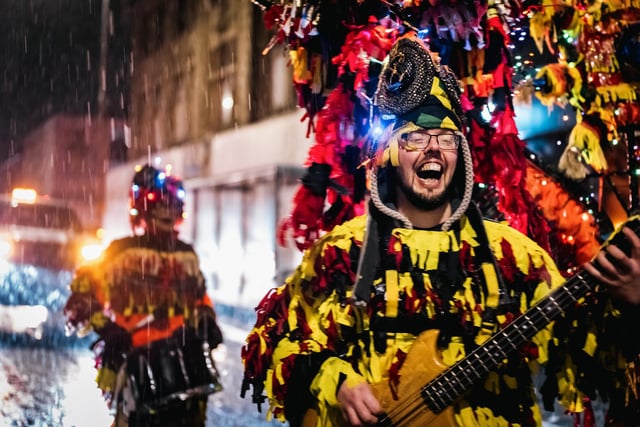 A musician in colourful costume takes part in the lantern parade despite the sleet and snow.