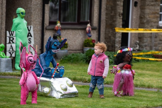 A child enjoys looking at the Lilo and Stitch scarecrows at the Wray Scarecrow Festival 2024 with a sci-fi theme.