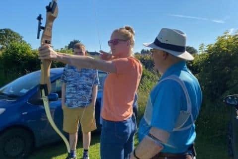Polly Swann has a go at archery, watched by Les Perkins from John O'Gaunt archery club.