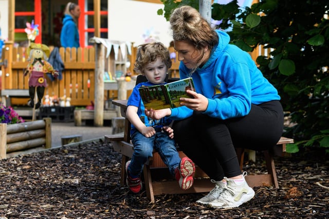 A nursery pupil enjoys a book in the new outdoor space.