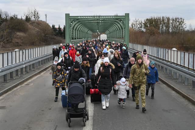 Ukrainian refugees walk a bridge at the buffer zone with the border with Poland in the border crossing of Zosin-Ustyluh, western Ukraine on March 6, 2022. - Over 1.5 million refugees have fled Ukraine in the week since the invasion by Russian on February 24, 2022, with over half going to Poland, according to the UN refugee agency. (Photo by Daniel LEAL / AFP) (Photo by DANIEL LEAL/AFP via Getty Images)