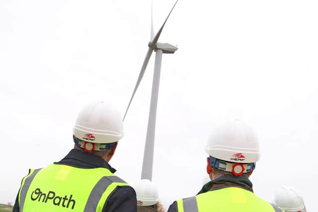 OnPath energy team members looking at a wind turbine.