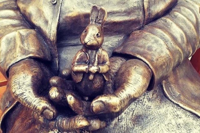 Peter Rabbit sits in the hands of the Beatrix Potter sculpture.