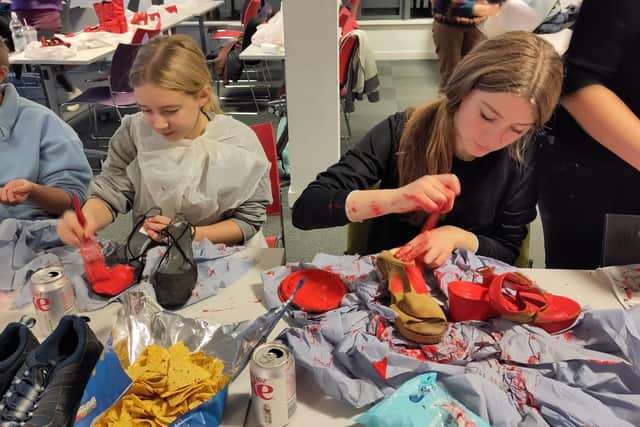 Volunteers prepare red shoes for the exhibition.