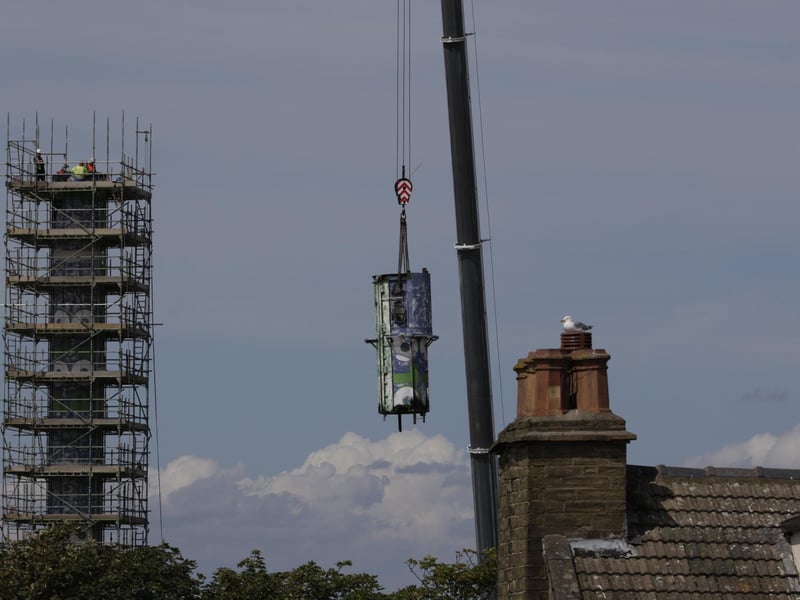 The top half of the tower is lifted away during the demolition process.