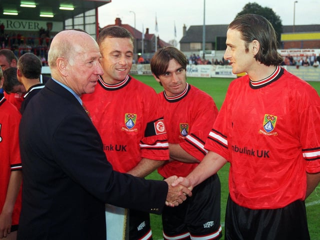 Sir Bobby Charlton shakes hands with Morecambe's Mickey Waller watched by Dave McKearney and John Kennedy during the official opening of the new Morecambe Stand at Christie Park.