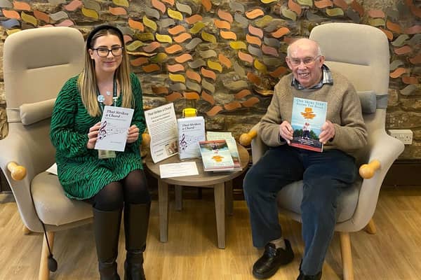 Author Tony Kadelbach with a member of the fundraising team at St John's Hospice holding one of his books.