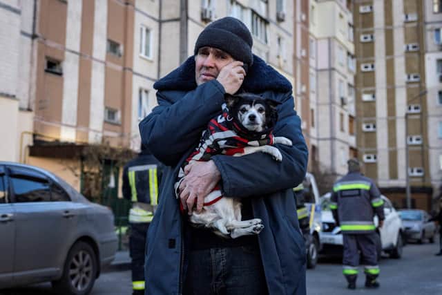 A resident carries his dog near a residential building which was hit by the debris from a downed rocket in Kyiv on March 17, 2022. - One person was killed and three injured when debris from a downed rocket hit a Kyiv apartment block, as Russian forces press in on the capital, emergency services said. Russian troops trying to encircle Kyiv have launched early morning strikes on the city for several successive days, putting traumatised residents further on edge. (Photo by FADEL SENNA / AFP) (Photo by FADEL SENNA/AFP via Getty Images)